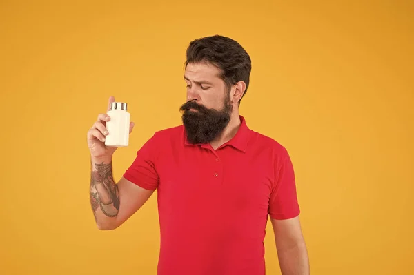 Investment in health. Side effects. Medicines concept. Food additives vitamins for male health. Vitamin complex. Handsome bearded man take medication. Health care. Hipster hold plastic container