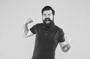 Zafer ve başarı. Sıradan giyinmiş sakallı adam kutlama yapıyor. Mutluluk ve neşe. Kazanan ve kazanan. Neşeli adam. İç enerji. Başarı için motive. Mutlu adam başarısını sarı arka planda gösterir.
