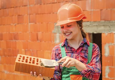 Harika bir süreç. Çocuk mühendis mimar. Gelecekteki evini inşa ediyor. Mutlu çocukluk. Çocuk koruyucu kask takıyor. İnşaat alanındaki kafayı koruyun. Kız tuğla tutuyor. Tuğlalı küçük inşaatçı