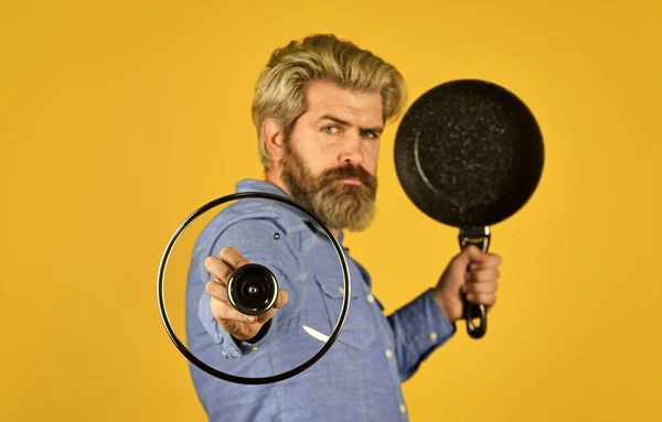 Cuisiner des aliments sains. Hipster barbu préparant le petit déjeuner. Conseils de friture. Shopping d'ustensiles de cuisine. Des ustensiles de cuisine. Vases de cuisson en fonte émaillée. Poêle antiadhésive surface en porcelaine. Homme tenir nouvelle casserole — Photo