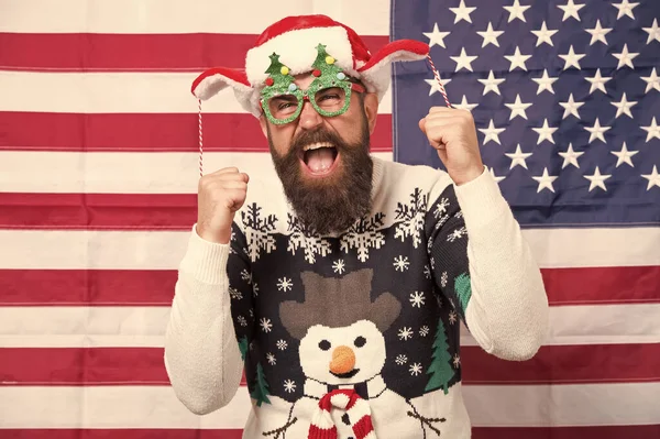 Jultraditioner och sedvänjor har förändrats mycket med tiden. Amerikanska skäggiga hipster killen gick glad fest. Amerikansk tradition. Jultomten på amerikansk flagga. Vintersemester — Stockfoto