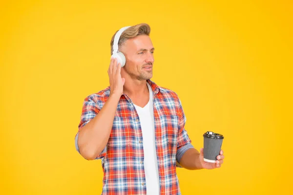 Homem caucasiano de meia-idade ouvir música em fones de ouvido segurando xícara de café quente, tempo de pausa — Fotografia de Stock