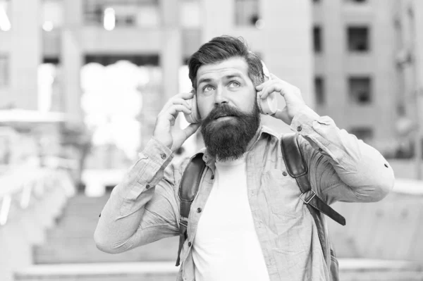 We hebben onze oren in de straten. Een man met een baard draagt buiten oortelefoons. Hipster luistert naar muziek in een koptelefoon. Comfortabele oorkussens. Gehoorbescherming. Het moderne leven. Oorkennis voor je ziel — Stockfoto