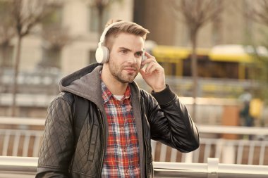 Müzik, ses ve teknoloji. Yakışıklı adam dışarıda kulaklık takıyor. Traşsız adam sokakta müzik dinler. Yeni teknoloji. HiFi teknolojisi. Modern müzik teknolojisi. Modern hayat