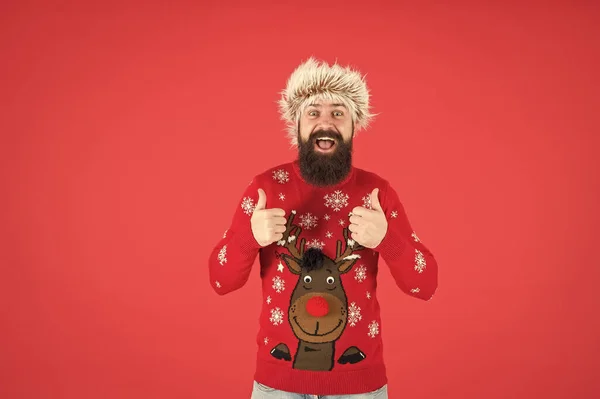 Boldog új évet! Szakállas férfi, vörös háttérrel. Vicces férfi szakállal kötött pulóverben. sikeres hipster készen áll a karácsonyi partira. téli ünnepség. hideg időjárás divat férfiaknak — Stock Fotó