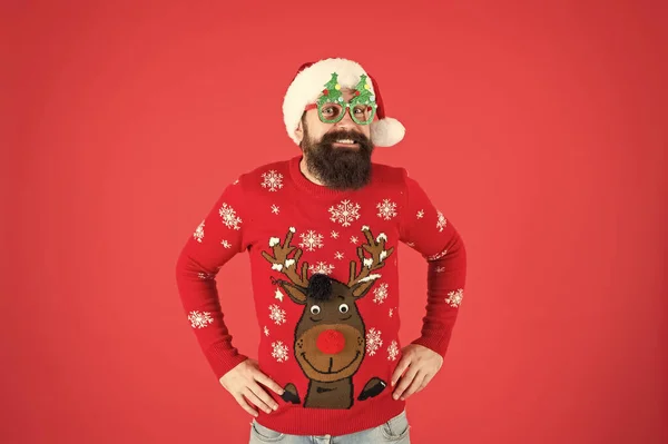 Just in time for Christmas. funny hipster knitted sweater. warm clothes for cold weather. bearded man santa hat red background. merry christmas. male in xmas party glasses. happy new year — Stock Photo, Image