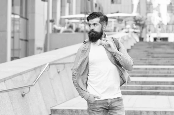 Vida moderna. Mudança de conceito de cenário. Bonito hipster com mochila andando rua. Caminhando pelas ruas vazias. Homem com auscultadores a andar no centro da cidade. A ouvir música. Rota diária para o trabalho — Fotografia de Stock