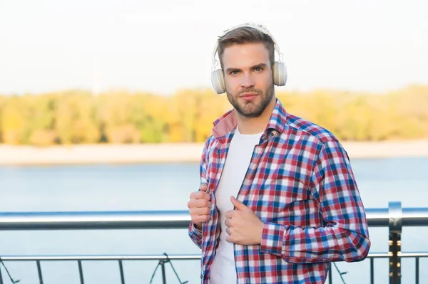 Γενειοφόρος άνθρωπος ακούστε μουσική σε ψηφιακά ακουστικά φορώντας καρό πουκάμισο εξωτερική, αντίγραφο χώρου, casual στυλ — Φωτογραφία Αρχείου