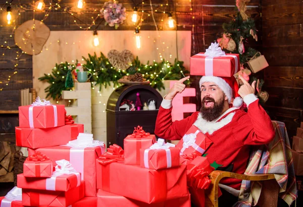 Los regalos de paquetes serán entregados a su destino. Enviando regalos. El hombre barbudo se sienta en un sillón con un montón de regalos. Saludos desde Santa. Residencia de Santa Claus. Vacaciones de invierno. Ambiente acogedor en casa — Foto de Stock