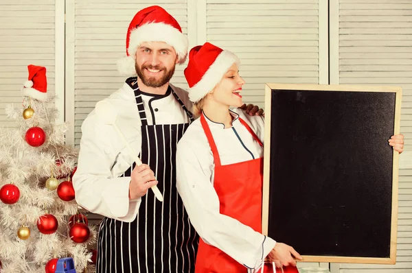 Homem e mulher chef Papai Noel chapéu perto da árvore de Natal. Conceito de receita de Natal. Casal preparando refeição vegetariana saudável juntos para o jantar de Natal. Ingrediente secreto é amor. Cozinhar refeição de Natal — Fotografia de Stock