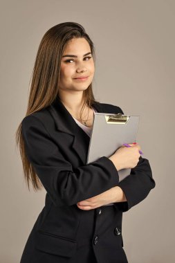 Bir sonraki adımı düşünürsek. Ceketli seksi kız klasörü tutuyor. Başarılı kadın belgelerle çalışıyor. Kendine güvenen bir ofis çalışanı Moda güzelliği. Resmi moda tarzı. Moda makyajlı esmer kadın.