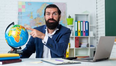 Sakallı ve bıyıklı bir adam üniversitede ya da okulda iş adamı ya da öğretmen gibi görünüyor.