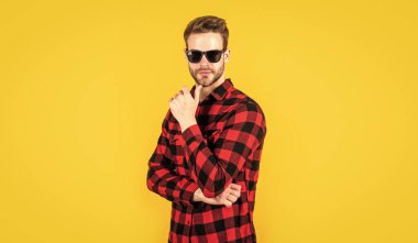 Her şey mükemmel olmalı. Kareli baskılı klasik erkek gömlekleri. Tişört ve gözlük takan kendine güvenen genç adam. Seksi adam bakıyor. Gömlekli yakışıklı bir adamın portresi.