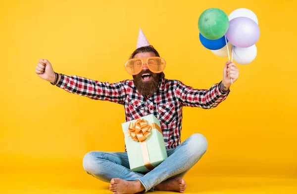 To mój dzień. Człowiek z pudełkiem z okazji urodzin. Dojrzały hipster z jasnymi kolorowymi balonami. Szalony zabawny facet. Zrelaksowany, szczęśliwy solenizant wygląda wesoło. brodaty mężczyzna poczuj radość — Zdjęcie stockowe