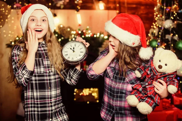 Holiday atmosphere. Little girl sisters in red hats. We are family. Elf children. Xmas tree. Santa little girls sisters. Christmas time. Family holiday. Happy sisters. Happy new year. Family party