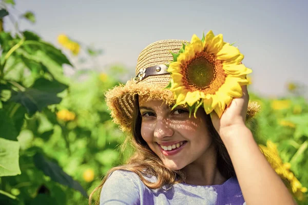 Kicsi szépség. Egy kislány a nyári napraforgómezőn. Boldog gyermeknapot! Gyerekkori boldogság. boldog gyerek portréja gyönyörű napraforgóval. vidám gyermek szalmakalapban sárga virágok között — Stock Fotó