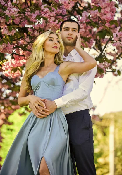 Prettige tijd door te brengen. Verliefd stel kussen en omhelzen. voorjaarsbloei. Man en vrouw in het park met roze bloeiende kers. schoonheid en mode. Fijne huwelijksreis. romantisch paar onder sakura boom — Stockfoto