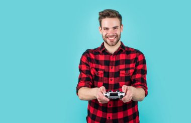 Moda saç stili olan şık bir adam kareli gömlek giyer video oyunu oynar, hobi yapar.