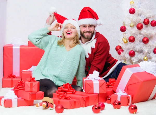 Pár nosit klobouky jako Santa Claus vánoční strom pozadí. Je snadné šířit kolem sebe štěstí. Veselá rodina slaví Vánoce. Vánoční dárek. Pár v lásce užijte si vánoční oslavu — Stock fotografie