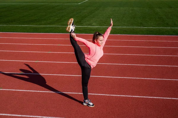 Stres atmak için. Beden eğitimi dersinde çocuk eğitimi. Kız antrenmandan önce geriniyor. Jimnastikçi yarışmaya hazırlan. Sporcu stadyum spor salonunda ısınıyor. esneklik — Stok fotoğraf