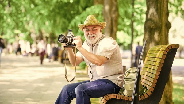 Time to relax. old man relax on bench. man tourist use camera take photo. concept of photography. senior bearded man photographing outdoor. professional photographer designer. happy retirement