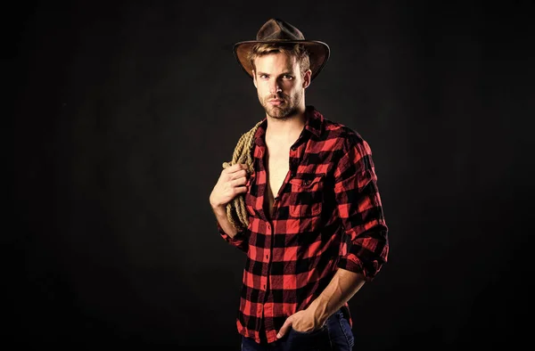 Heating up wild west. wild west rodeo. man in hat black background. man checkered shirt on ranch. Vintage style man. Wild West retro cowboy. cowboy with lasso rope. Western. western cowboy portrait — Stock Photo, Image