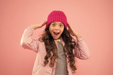 İyi eğlenceler. Çocuklar için mevsimlik moda. Küçük pembe duvar. Küçük kız kabarık ceket ve örgü şapka. Soğuk havada sağlık hizmeti. Havası ne olursa olsun. Sıcak kış kıyafetleri içinde mutlu bir çocuk.