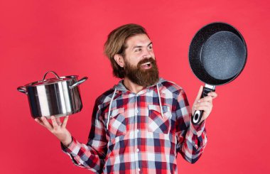 Havalı, bakımlı, sakallı, tavayla yemek pişiren, yemek pişiren bir hippi.