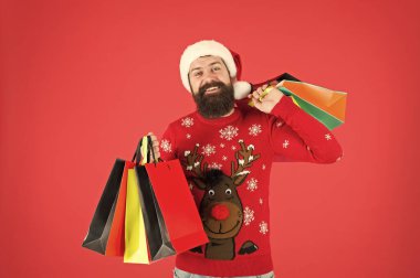 Organize bir müşteri. Kompülsif alıcı. Perakende. Neredeyse Noel 'de. Aileye hediyeler. Sakallı hippi alışveriş çantası taşır. Noel Baba hediye aldı. Noel hediyeleri. Geyikli yılbaşı kazaklı adam.