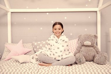 Evde iyi hissediyorum. Yatak odası derli toplu. Küçük bir kız için hoş bir yatak odası. Kız yatak odasının içinde eğleniyor. Çocukluk konsepti. Yatak odası dinlenme ve dinlenme yeri. Pijamalı çocuk. Mutlu sabahlar