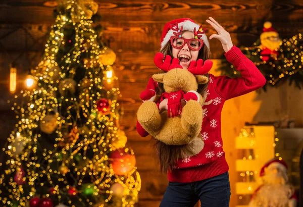 最愉快的假期快乐的小女孩拿着驯鹿玩具礼物。新年派对庆祝活动。圣诞节的时候到了。这是有史以来最好的礼物童年的快乐穿着圣塔服装的快乐的孩子。爱孩子的圣诞节 — 图库照片