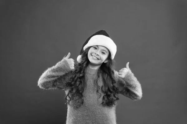 Vacanza davvero buona. vacanza invernale preferita. Mi diverto. Piccolo Babbo Natale. mi sento felice per il nuovo anno. tempo per le vacanze di Natale. bambina in cappello da Babbo Natale. allegro bambino muro rosso. inverno capretto moda — Foto Stock