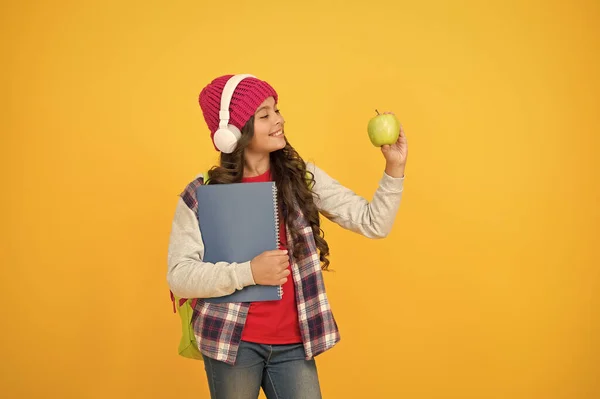 Hábitos alimenticios saludables para su hijo. Chica feliz mantenga fondo amarillo manzana. Disfrutando de un aperitivo escolar saludable. Aperitivos y dietas saludables. Ofrecer comida saludable en la escuela. Educación en línea — Foto de Stock