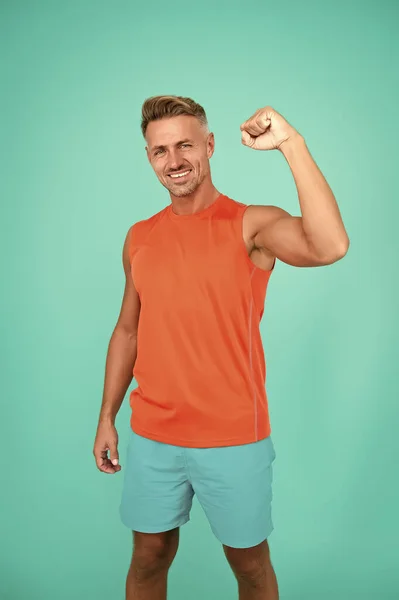 Steigern Sie Ihre sportliche Leistung. Glücklicher Mann fix Arm blauer Hintergrund. Fitte Kerle zeigen Muskelkraft. Sportbekleidung und Sportbekleidung. Macht und Stärke. Training für die Macht. Fitness und Sport — Stockfoto