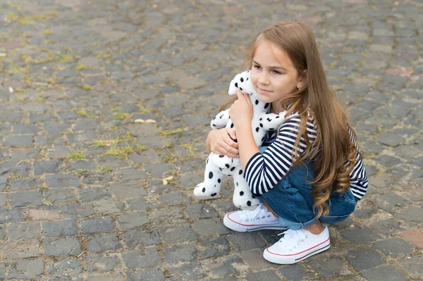Brincadeira de criança pequena bonito com cão de brinquedo sentado no pavimento de seixos ao ar livre, jogando, espaço de cópia — Fotografia de Stock