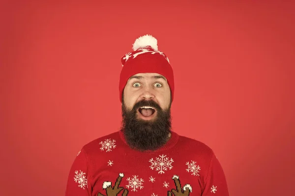 A vida é surpreendente. Homem hipster usar chapéu de malha de inverno. Barbearia e pelos faciais. Cuidados com a pele de inverno. Um tipo com roupas de inverno e acessório. Cara barbuda fechar fundo vermelho. Férias de inverno — Fotografia de Stock