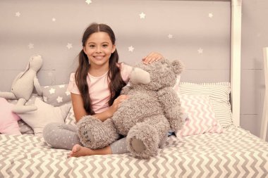 Hayali etkileşim. Oyun oynayın. En sevdiği oyuncak. Kız, yatak odasında oyuncak ayıya sarılıyor. Yatak odasında güzel vakit geçiriyoruz. Uzun saçlı tatlı pijamalı kız rahatla ve pelüş oyuncak ayı oyna..