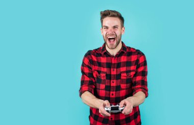 Dijital dünyada yaşamak. Erkek hobisi ve boş zaman. Kareli tişörtlü bir oyuncu. Sakallı adam oyun konsolu kullanıyor. joystick 'li traşsız yakışıklı adam. bilgisayar ve çevrimiçi oyun oyna