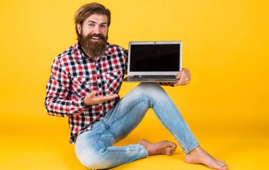 Bilgisayar ustası ürünü sunuyor. Dijital yaşam tarzı kavramı. Bilgisayarda çalışan olgun bir öğrenci. Adam defter üzerinde çalışıyor. İnternetten alışveriş. Neşeli hippi bilgisayar kullanıyor. iş dünyasındaki modern teknoloji