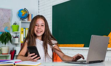 Mutlu bir gün. Çocukluk gelişimi. İnceleme yoluyla bilgi edinmek. Sınıfta tahtası olan bir çocuk. Çocuk bilgisayarı kullanıyor. Okula dönüyorum. Modern hayatta çevrimiçi resmi eğitim. evde eğitim kavramı