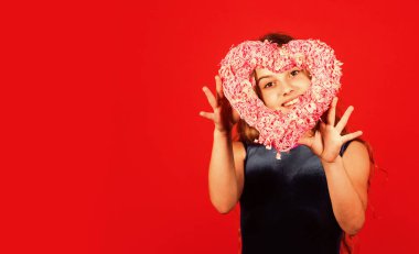 Romantik bir ruh hali. Mutlu çocuk kalbini kırmızı arka planda tut. Pembe kalpli küçük bir kız. Kalp şeklinde dekoru olan sevgililer günü. Sevgi ve ilgi tatili. Sevildiğimi hissetmek. Güzel bebek. Sevimli kız eğleniyor