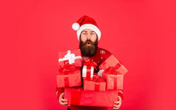 Kerstmis is tijd om te geven. Nieuwjaarskorting. Een bebaarde kerstman met hoed. Vier het feest. Klaar voor kerstcadeaus. Kerstfeest. volwassen man in trui rode achtergrond — Stockfoto