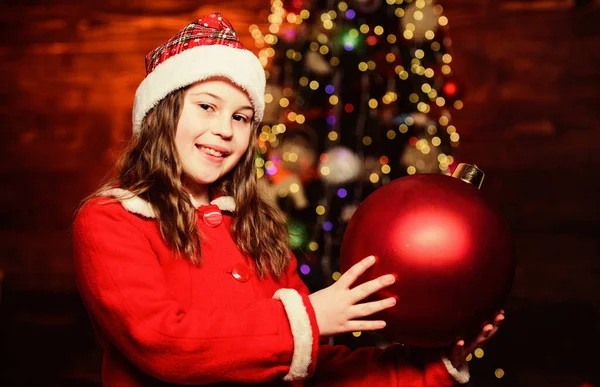 Noel süsleri. Etraftaki her şeyi dekore et. Köpüklü oyuncak. Noel ağacı süslemeyi seviyorum. Şenlikli atmosfer noel günü. Kız Noel Baba kostümü büyük bir balo ağacı süsü içerir. — Stok fotoğraf