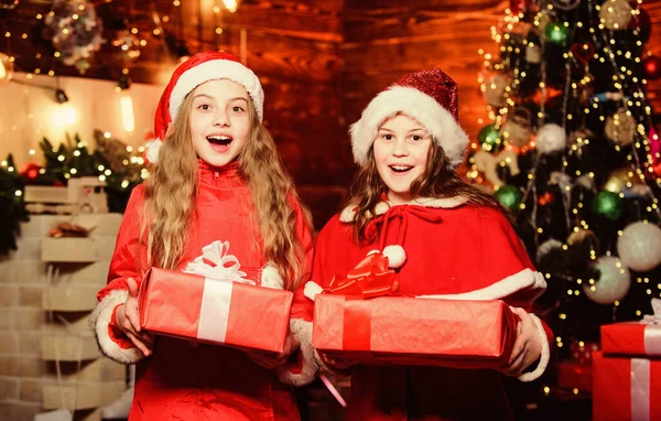 神奇的一刻 精灵的孩子。 圣诞节的孩子。 圣诞节的时候 精灵的孩子。 戴着红帽子的小女孩姐姐们。 圣诞精灵 新年快乐。 孩子们喜欢精灵 带礼品盒的圣诞老人妹妹 — 图库照片