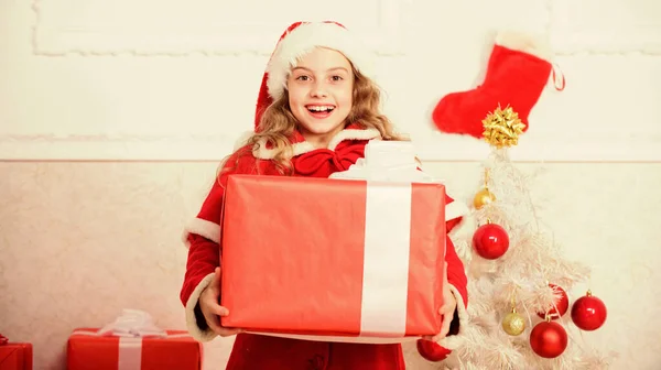 Wigilia nadeszła. Rozpakowuję świąteczny prezent. Zimowa tradycja wakacyjna. Dzieciak zadowolony z prezentu świątecznego. Dziewczyna świętować Boże Narodzenie otwarte pudełko prezentów. Mikołaj przynieś jej prezent. Sprzedaż zakupów zimowych — Zdjęcie stockowe