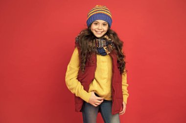 Temiz hava için modaya uygun kıyafetler. Moda tarzı kırmızı arka planda mutlu bir kız. Küçük çocuğun modaya uygun görünüşü. Kış tarzı. Moda ve güzellik. Modaya uygun ve zarif.