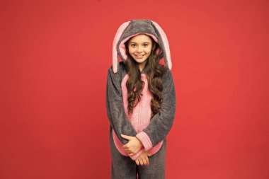 Her gün şirinsin. Hoş bir çocuk kırmızı arka planı. Sevimli kız tavşan pijaması giyer. Şirin görünümlü küçük bir çocuk. Paskalya. Bahar. Baykuşun gibi ol.