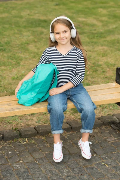 Bambino felice ascoltare musica in cuffie moderne seduti sulla panchina del parco estate all'aperto, vacanza — Foto Stock