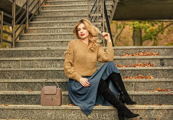 Fall fashion trend. Wearable trends. Layer oversize knit over girly skirt. Fall outfit formula. How to Style Sweater and Skirt Combo for Fall. Woman with gorgeous hairstyle sit on stairs outdoors — Stock Photo, Image
