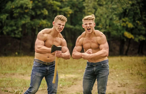 いい兄弟だ。陸上の双子は斧を使う。筋肉質の胴を持つ男性。遺伝学の概念。同胞団の友情。強さと忍耐。強い男の性質の背景。斧を持つグループの筋肉の男性 — ストック写真
